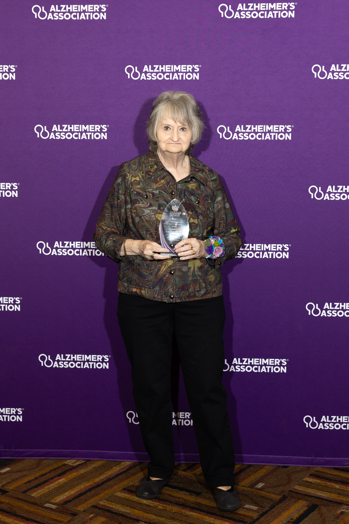 Carrie Russert poses with her LAY award in front of a purple Alzheimer's Association background