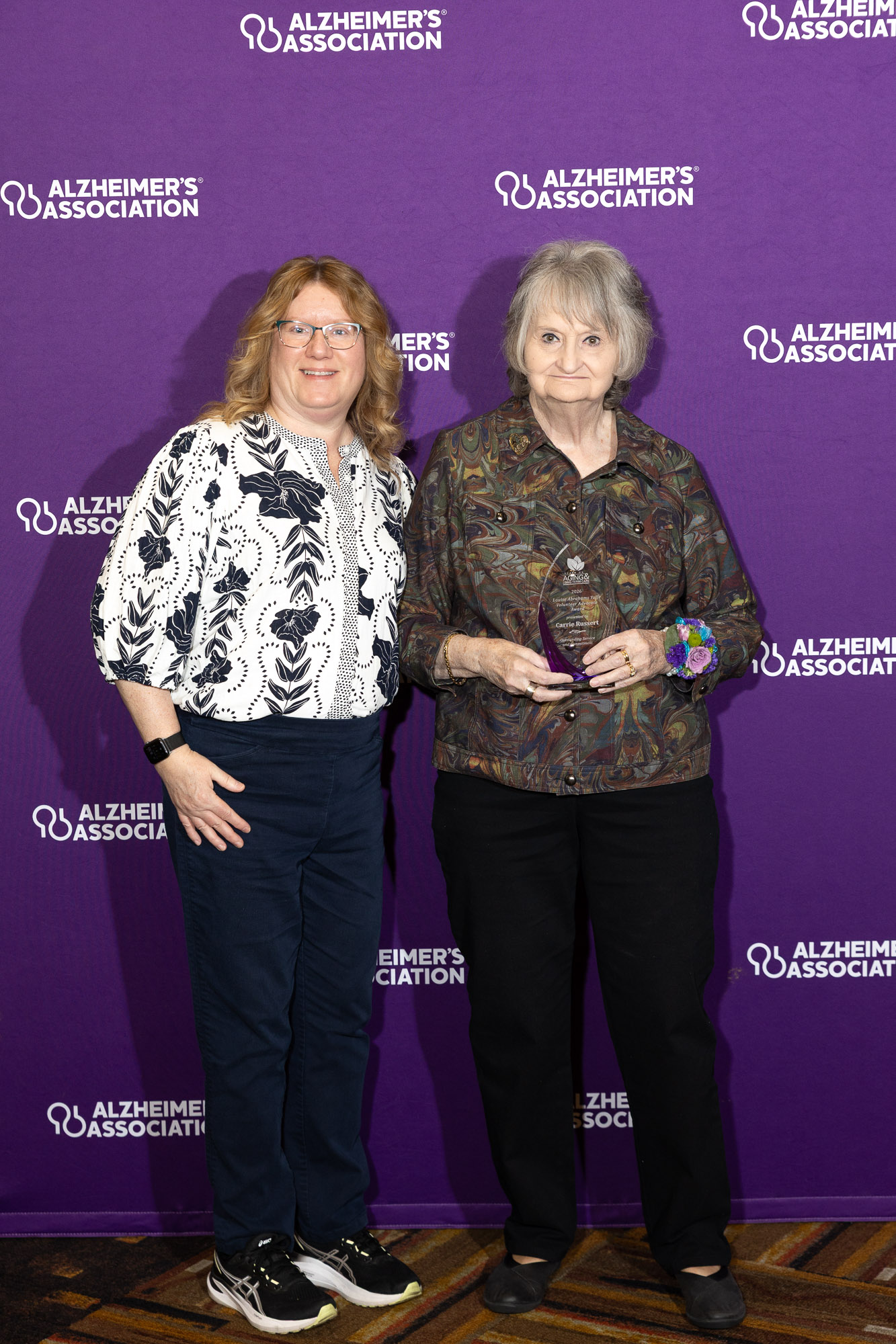Carrie Russert and Mary LeMay pose in front of a purple Alzheimer's Association background